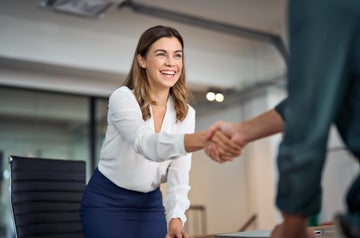 Happy mid aged business woman manager handshaking greeting clien